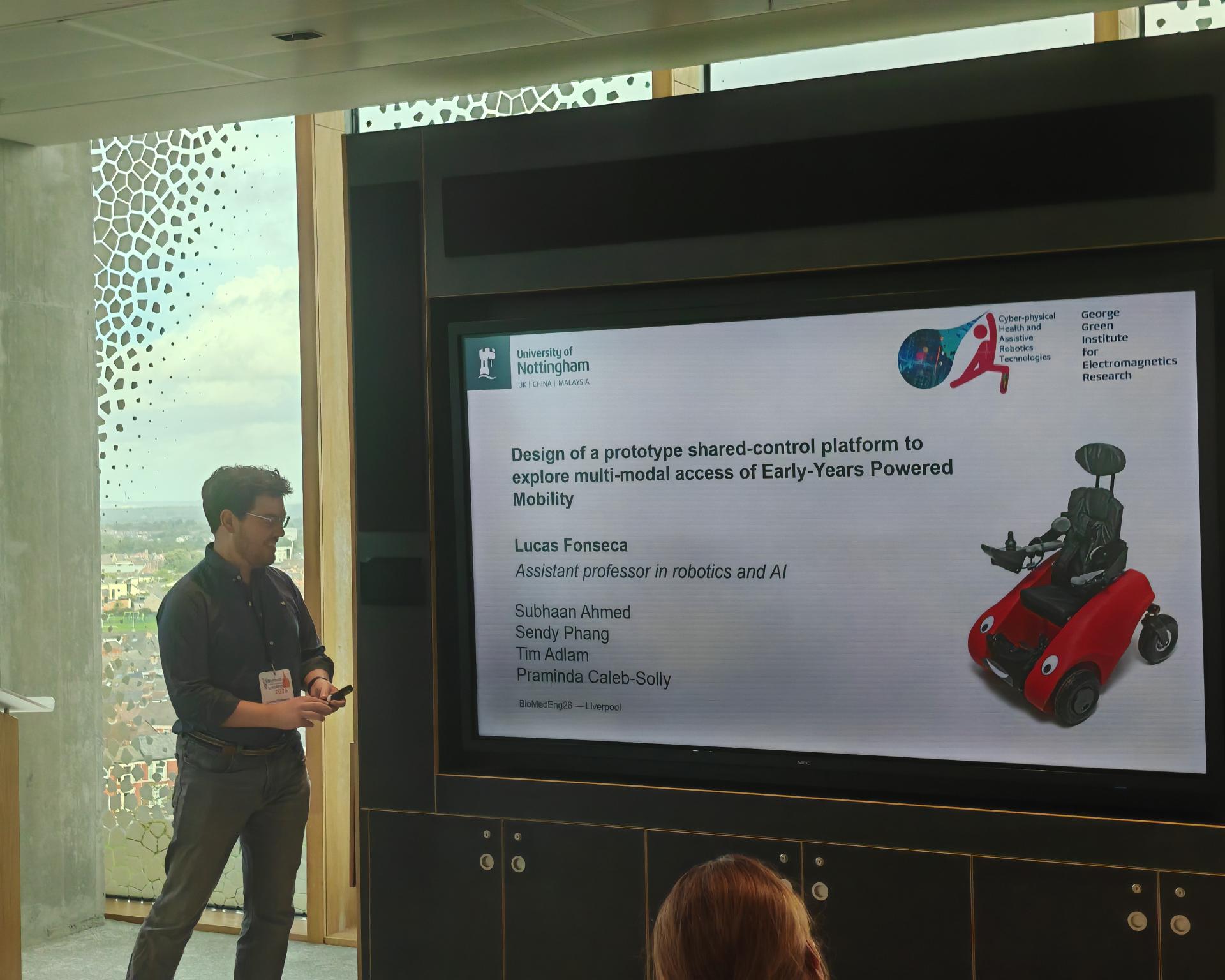 Lucas Fonseca presenting the SMILE shared-control prototype at BioMedEng 2026; the slide shows the mobility platform.